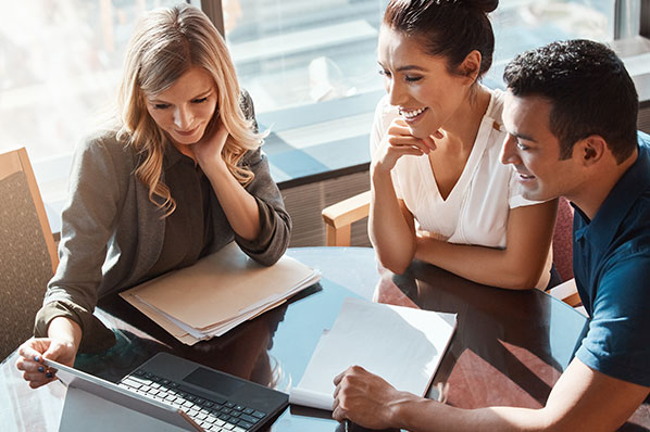 A couple reviewing documents with a financial advisor at a table