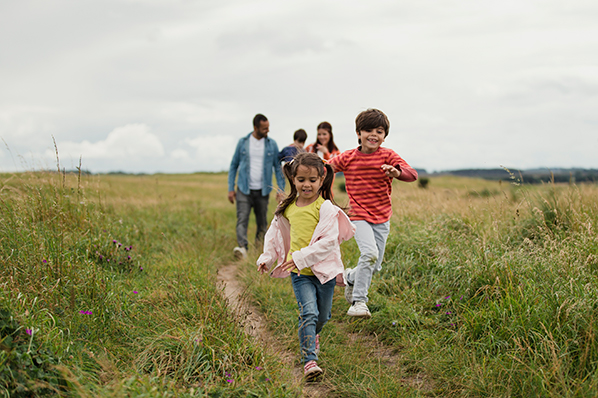 A family of five running along a trail on an open field