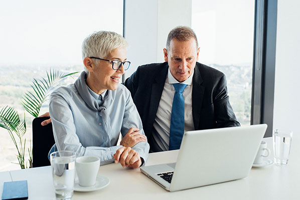 An older couple sitting at a table using a laptop
