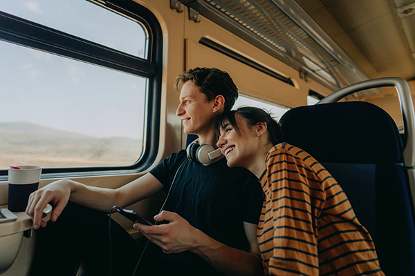 young couple sitting on a train looking out the window