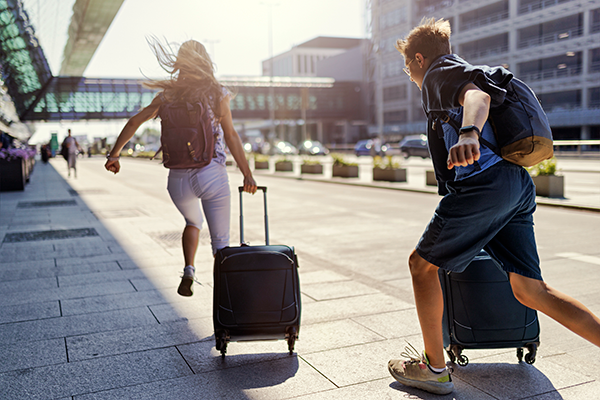 a young couple running with their luggage into the airport