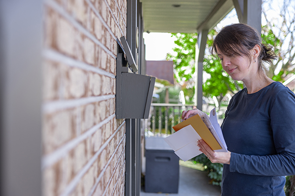 A woman placing mail into a mailbox