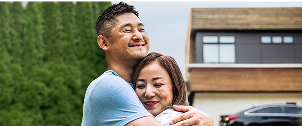 A man and a woman embracing in front of a house