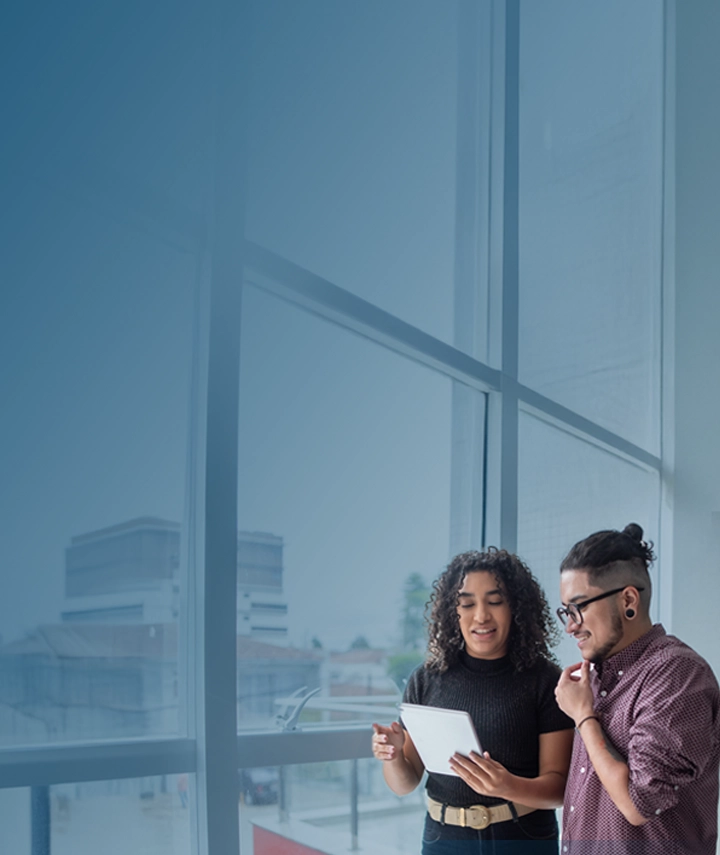 A woman and man chatting while reading a tablet