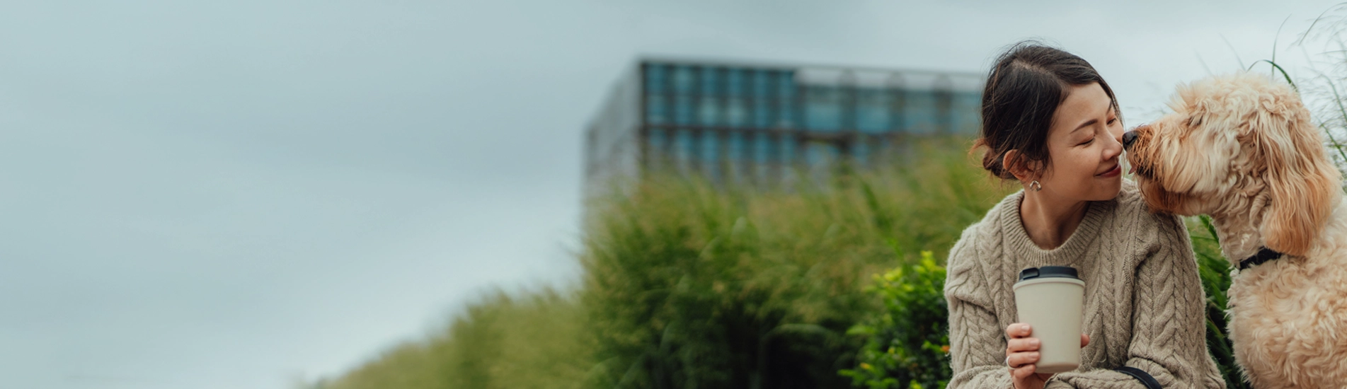an Asian woman in her 30s leaning in to snuggle with her fluffy white dog