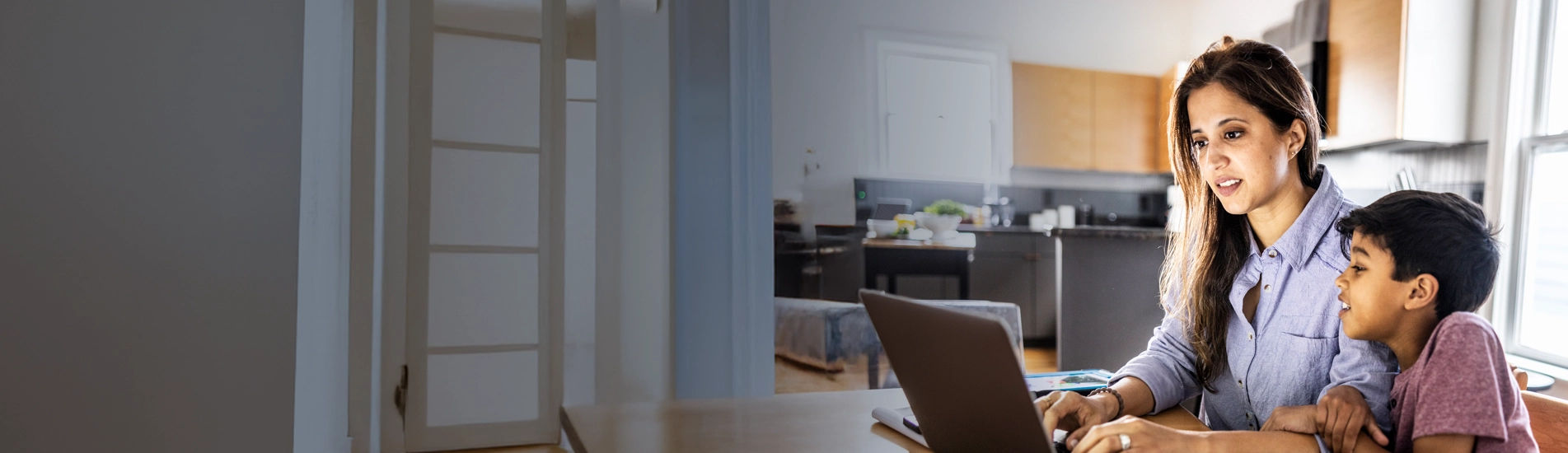 A woman on a laptop sitting next to her son